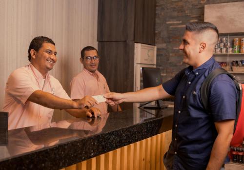 a man handing a man a piece of paper at Hotel Santa Clara Boutique in Montería