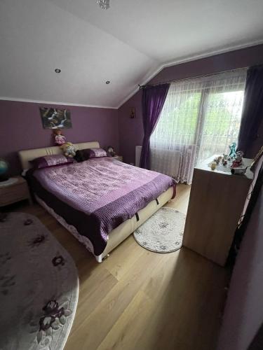 a bedroom with a purple bed and a window at Casa Iuliana Camelia in Câmpulung Moldovenesc