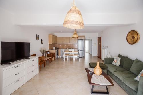 a living room with a green couch and a kitchen at THREE GRACES filikon in Zakynthos Town