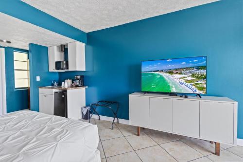a bedroom with a bed and a tv on a blue wall at Oceanfront Inn, Private Balcony, 2 Full Beds #16 in Fort Pierce