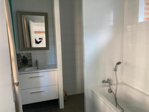 a bathroom with a tub and a sink and a mirror at Gite du point du jour - Prêt de velos in Luc-sur-Mer