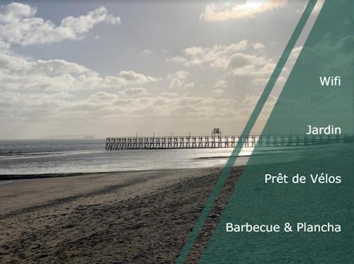 une photo d'une plage avec une jetée en arrière-plan dans l'établissement Gite du point du jour - Prêt de velos, à Luc-sur-Mer