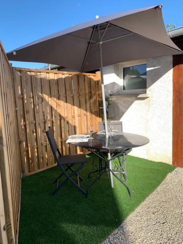 une table avec un parasol à côté d'une clôture dans l'établissement Maison avec piscine, à Fondettes