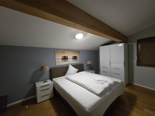 a bedroom with a white bed and a white cabinet at Walensee House & Apartments in Unterterzen