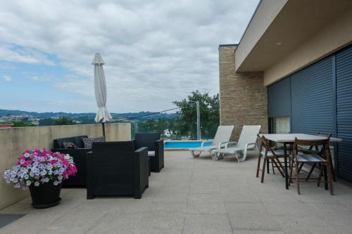 马尔科-德卡纳维泽斯Casa Moderna na Aldeia的带椅子、桌子和遮阳伞的露台