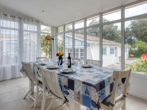 une salle à manger avec une table, des chaises et des fenêtres dans l'établissement Holiday Home Petite Ensouleihado by Interhome, à Soulac-sur-Mer