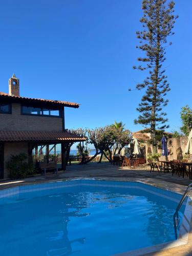 a swimming pool in front of a resort with a tree at pousada sudoeste castelhana in Saquarema