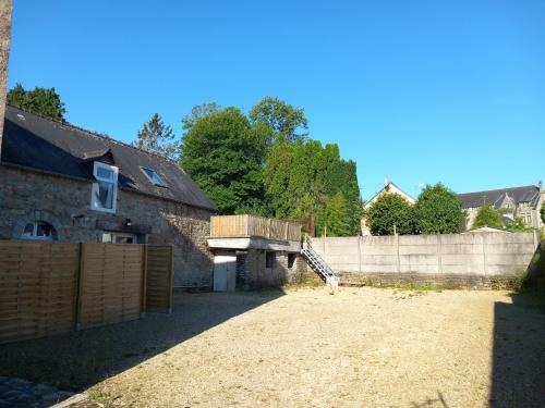une arrière-cour avec une clôture en bois et une maison dans l'établissement Odet, maison avec grande terrasse, à Rosporden