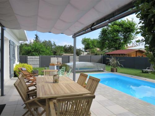 un patio avec une table et des chaises à côté d'une piscine dans l'établissement Villa Villa Camélia by Interhome, à Andernos-les-Bains
