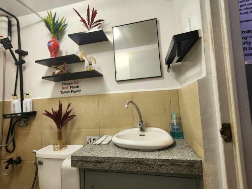 a bathroom with a sink and a toilet and a mirror at Aura Suite in Imus