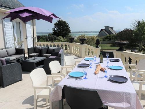 une table avec des chaises blanches et un parasol sur une terrasse dans l'établissement Villa La Sanaga by Interhome, à Plounéour-Trez