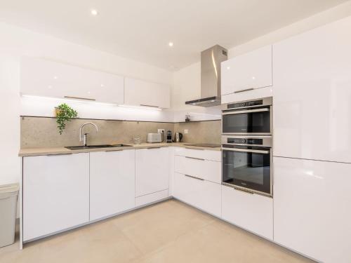 une cuisine blanche avec des armoires et des appareils blancs dans l'établissement Apartment Akemi by Interhome, à Sainte-Maxime