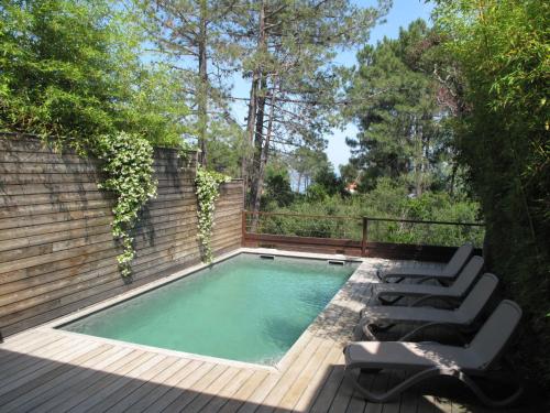 a swimming pool with two lounge chairs next to a wooden deck at Apartment Les Jardins d'Ève- F3 by Interhome in Favone