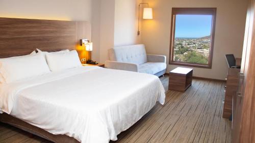 a hotel room with a bed and a chair and a window at Holiday Inn Express Guaymas by IHG in Guaymas
