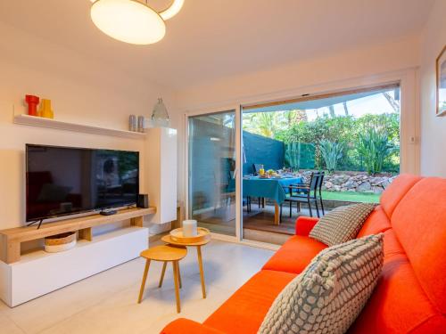 un salon avec un canapé orange et une télévision dans l'établissement Apartment Résidence Le Boréal-3 by Interhome, à Saint-Raphaël