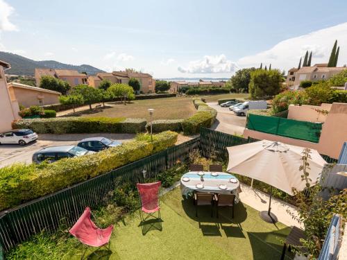 un patio avec une table, des chaises et un parasol dans l'établissement Holiday Home Les Jardins d'Hélios-3 by Interhome, à Carqueiranne