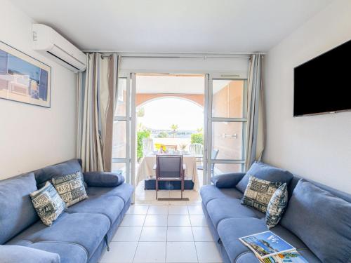 un salon avec un canapé bleu et une télévision dans l'établissement Apartment Le Village - E1103 by Interhome, à Saint-Raphaël