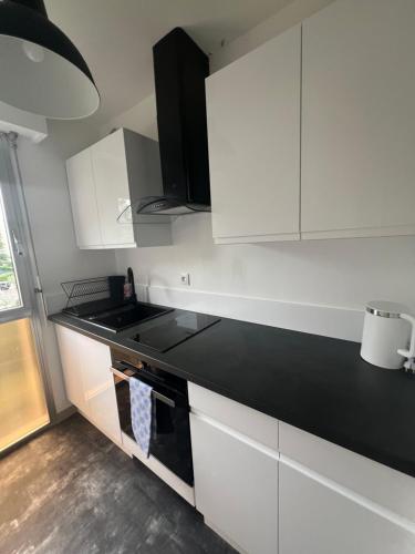une cuisine avec des armoires blanches et un comptoir noir dans l'établissement Appartement Les Oliviers, à Nice
