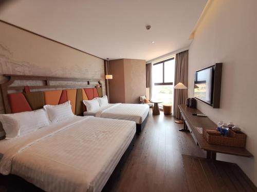 a hotel room with two beds and a flat screen tv at APEC Mandala Mũi Né in Mui Ne