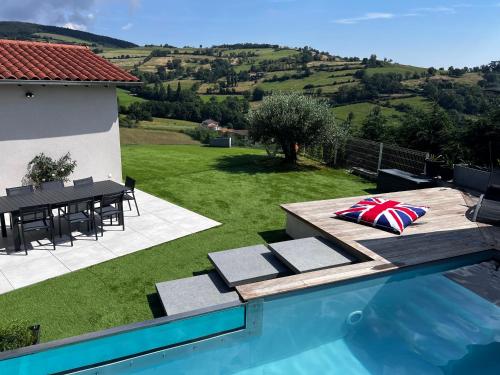 a house with a swimming pool with a table and a lawn at Maison et piscine chauffée, vue Monts du Lyonnais in Brullioles