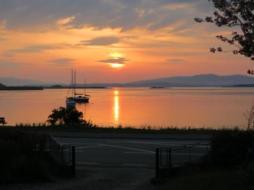 a boat sitting on the water at sunset at Holiday Home An Cala by Interhome in Oban