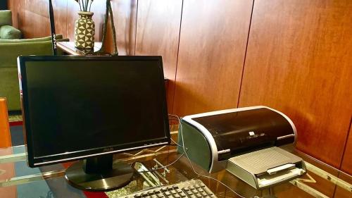 a computer monitor and a printer on a glass table at Hotel 3K Madrid in Lisbon