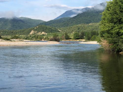 a river with trees and mountains in the background at Camping Shtepez in Gjirokastër