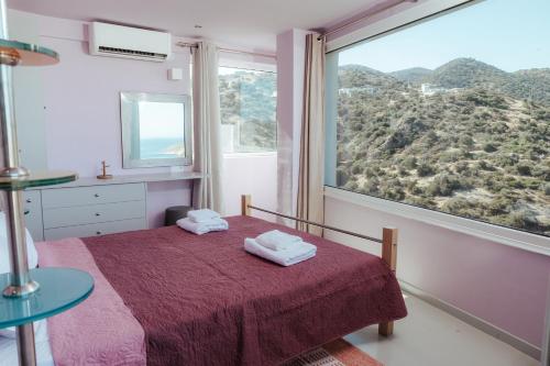 a bedroom with a bed and a large window at MountSea Villa in Agios Nikolaos