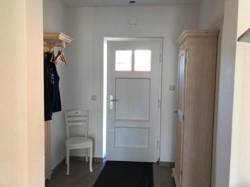 un pasillo con una puerta blanca y una silla en Haus Eisvogel, en Prerow