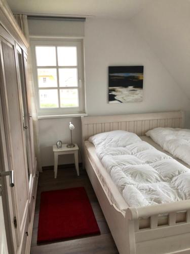 1 dormitorio con cama blanca y alfombra roja en Haus Eisvogel, en Prerow