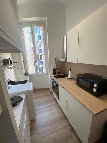 une cuisine avec des armoires blanches, un évier et un micro-ondes dans l'établissement République / La Joliette, à Marseille