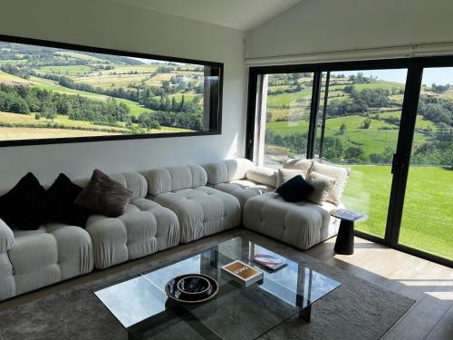 a living room with a white couch and a glass table at Maison et piscine chauffée, vue Monts du Lyonnais in Brullioles