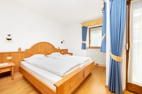 a bedroom with a bed with a blue curtain at Frara Residence Apartments in San Cassiano