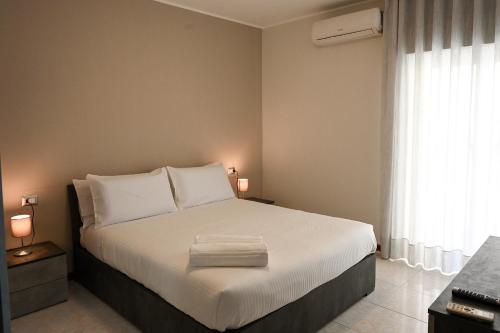 a bedroom with a bed with white sheets and a window at Casa Aricò in Calatabiano