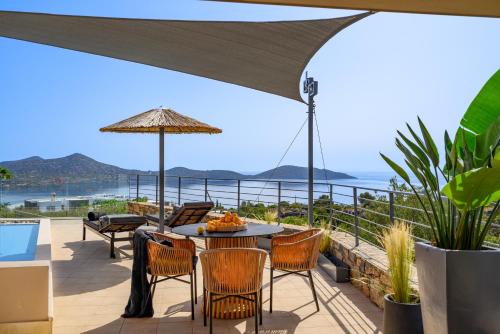 a patio with a table with chairs and an umbrella at Anemos Elounda Villas in Elounda