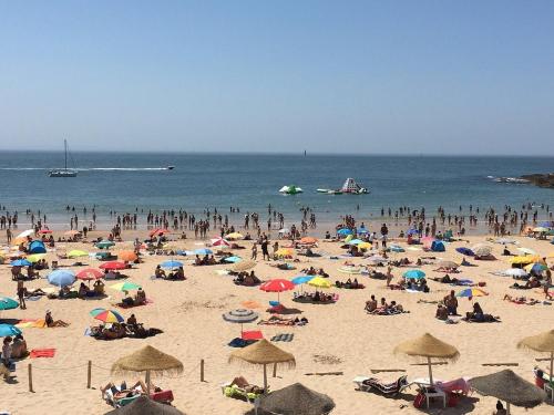 a crowd of people on a beach with umbrellas at AOMO ART SPACE Hostel in Oeiras
