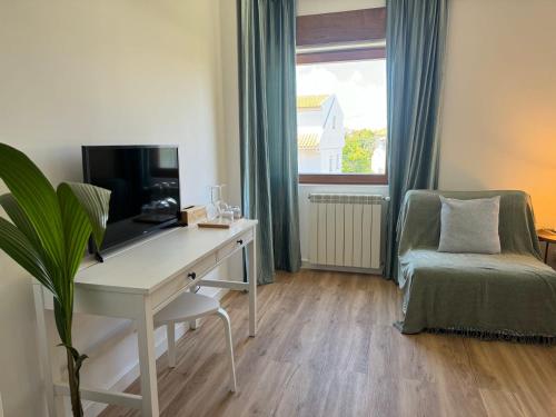 a room with a desk with a television and a chair at AOMO ART SPACE Hostel in Oeiras