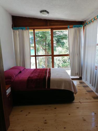 a bedroom with a bed and a large window at Cabaña Papá Beto in Mineral del Monte