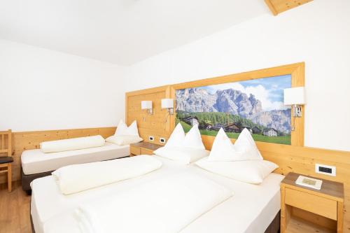 a hotel room with two beds and a large window at Ciasa Sopl&agrave; in San Cassiano