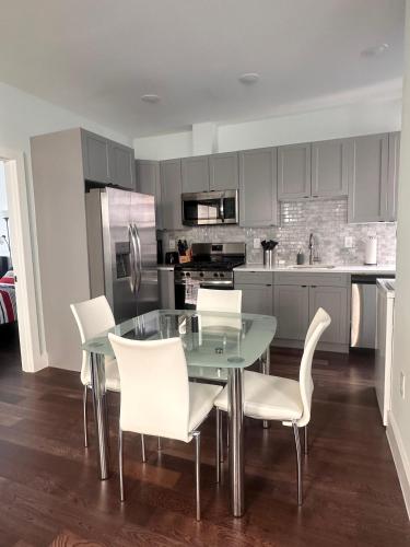 cocina con mesa de cristal y sillas blancas en Enjoy New York and Manhattan from Jersey City, en Jersey City