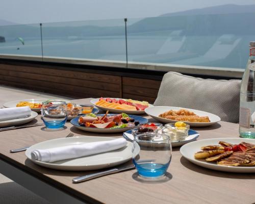 a table with plates of food on a table with the ocean in the background at Abi's Hotel & SPA Vlore in Vlorë