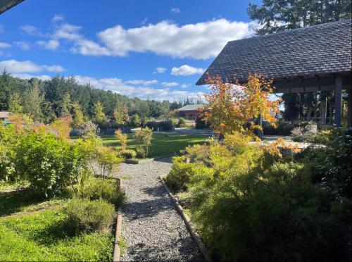 a garden with bushes and trees and a building at Departamento frente al lago in Llanquihue