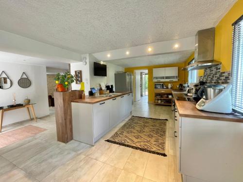 une grande cuisine avec des placards blancs et un comptoir dans l'établissement Charmante Spacieuse, à La Chapelle-de-la-Tour