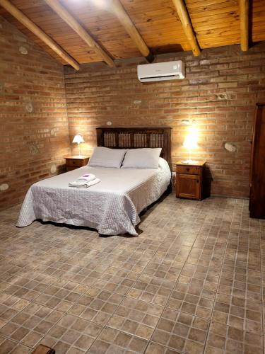 a bedroom with a bed in a brick wall at cabañas Villa de las rosas in Villa de Las Rosas
