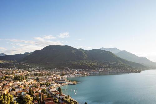 a view of a town on the water with mountains at A-ROSA Gardasee in Salò