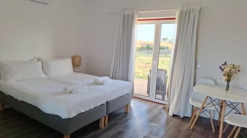 a bedroom with a bed and a table and a window at Monte da Isabel in Vale de Água