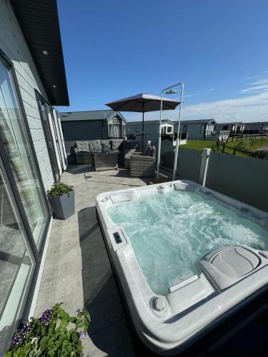 a jacuzzi tub on the patio of a house at Golden Anchor - The Oakland Lodge - Coastal Caravan Breaks in Chapel Saint Leonards