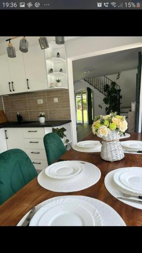 a table with white plates and a vase of flowers on it at VILA Ade in Padeş