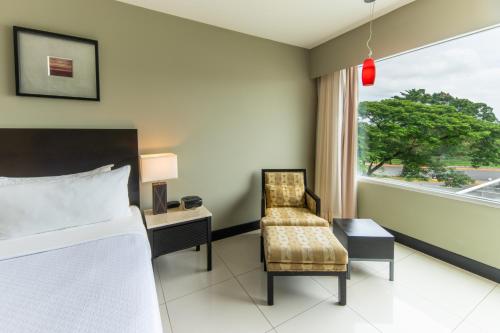 a bedroom with a bed and a chair and a window at Crowne Plaza Villahermosa by IHG in Villahermosa