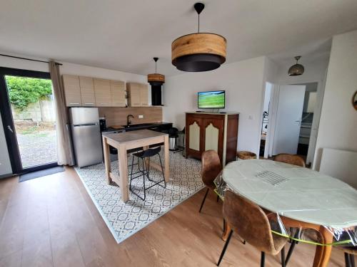 a living room with a table and a kitchen at Les Fleurs de Lin - logement neuf entre Etretat et Veules les Roses in Ouainville